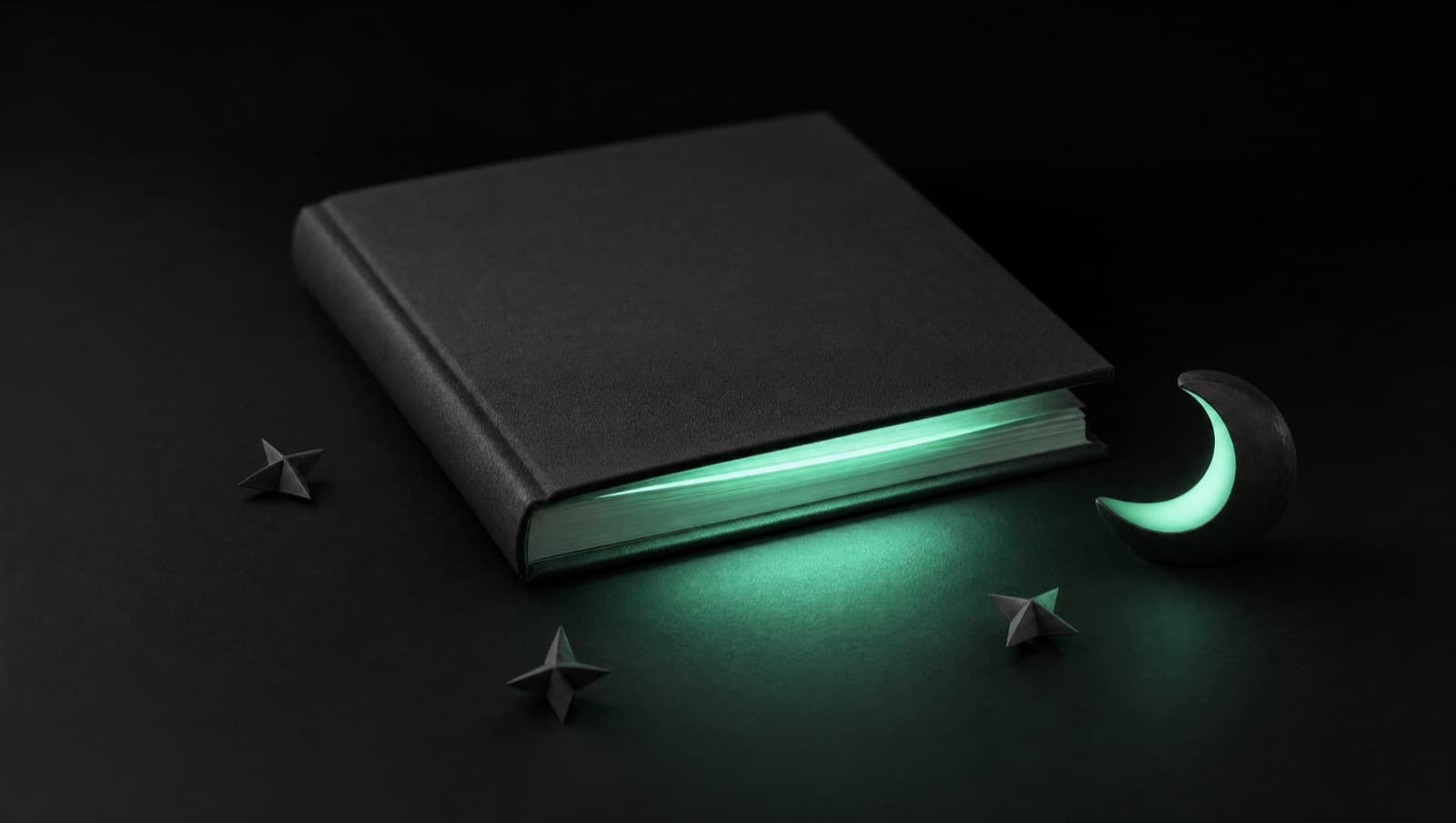 Закрытая чёрная книга, из-под обложки пробивается мятное свечение страниц, рядом бумажные звёздочки и светящийся полумесяц — нейросеть сочиняет сказки на ночь.